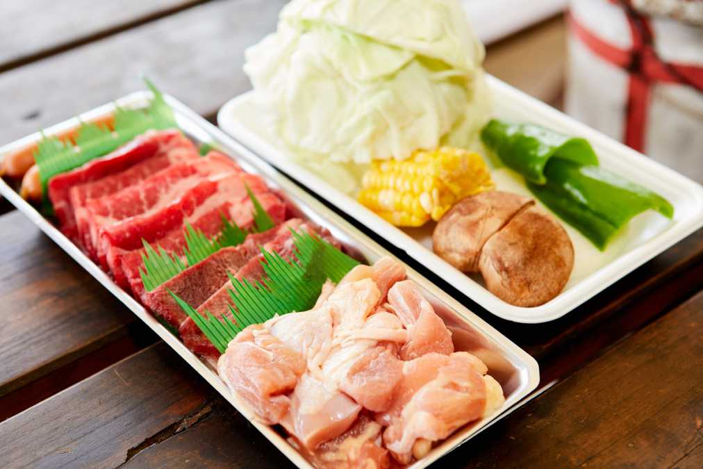 (手前)付属食材1人前(牛肉100g、牛タン30g、鶏肉120g、ソーセージ2本)、(奥)追加メニューの野菜盛り500円